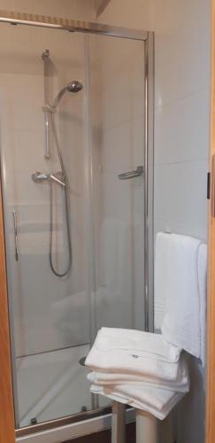 una ducha con una puerta de cristal junto a una mesa con una toalla en Locanda Il Burchiello, en Oriago Di Mira