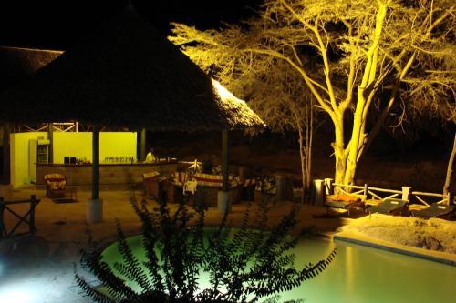 a night view of a resort with a swimming pool at Maneaters in Tsavo