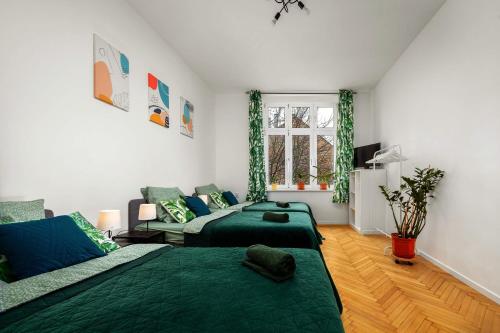 1 dormitorio con 2 camas verdes y sofá en Apartament blisko Wawelu, en Cracovia