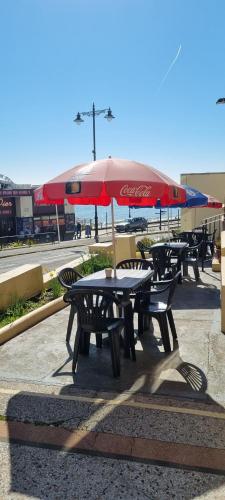 a group of picnic tables with a cocacola umbrella at Royal Pier in Sandown