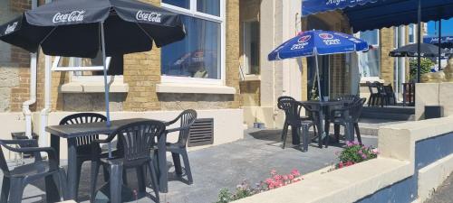 a group of black tables and chairs with umbrellas at Royal Pier in Sandown