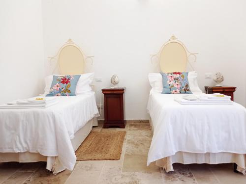 two beds with white sheets and pillows in a room at Giardino Frannicola in Maglie