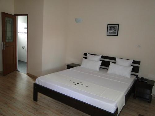 a bedroom with a large bed with white sheets and pillows at Hotel H1 Antsirabe in Antsirabe