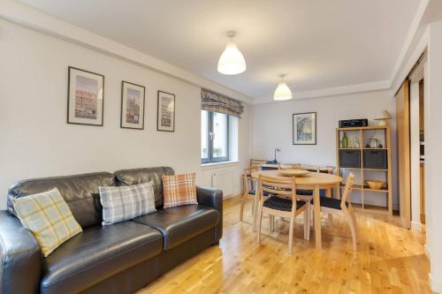 a living room with a leather couch and a table at *Amazing Location!*In heart of the City. 2BR & Cot in Edinburgh