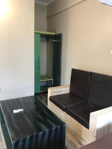 a living room with a black couch and a table at L&J Modern Backpackers Kinondoni in Dar es Salaam