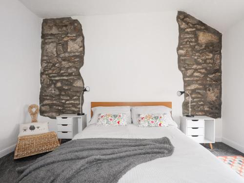 een slaapkamer met een groot bed en een stenen muur bij 5 Thomas Street in Llanberis