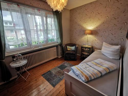 a bedroom with a bed and a table and windows at HR Townhouse Honigbach in Coesfeld