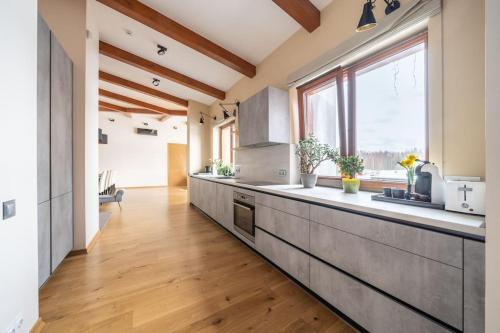 a kitchen with wooden floors and a large window at Dabas Mājas - Your Dream Holiday Spot in Vecslavēkas