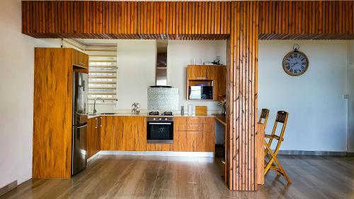 een keuken met houten kasten en een klok aan de muur bij Sunrise View villa in Bois-des-Amourettes
