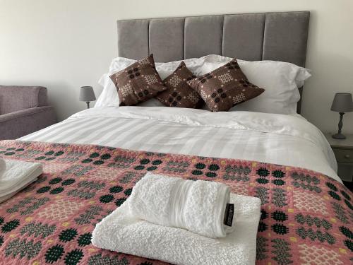 a bed with a blanket and pillows on it at Traeth Rooms in Cardigan