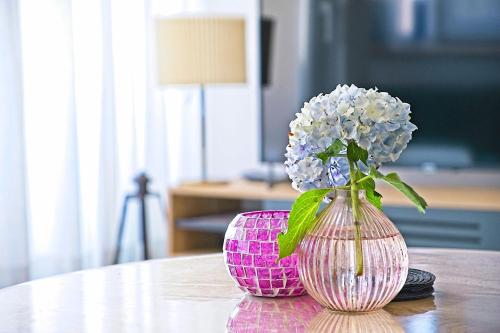 un vaso rosa con fiori bianchi su un tavolo di Apartment Postira a Postira (Postire)