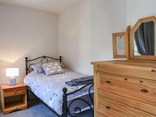 a bedroom with a bed and a dresser with a mirror at Cartwheel Cottage in Hawes