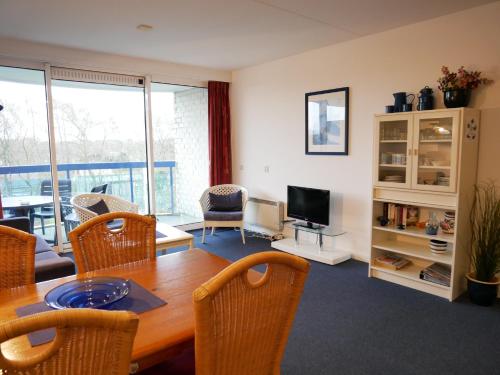 a living room with a table and chairs and a television at Badhotel Appartementen Callantsoog in Callantsoog