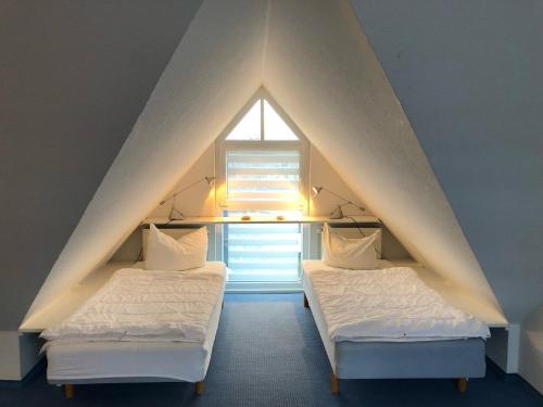 two beds in a attic room with a window at Stromstr_2 _Boddenblick_ Whg_26 in Zingst
