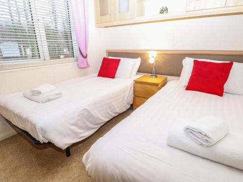 two beds in a room with red pillows at Manderine Lodge in Morpeth