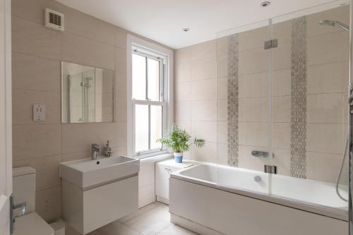 a white bathroom with a tub and a sink at Stunning double bedroom in 4 bedroom house in Peckam in London