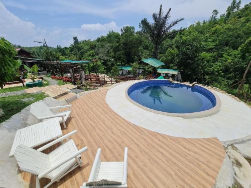 a swimming pool with two chairs and a wooden deck at CASA DEL PUEBLO DE CABANACAN in Bulacan