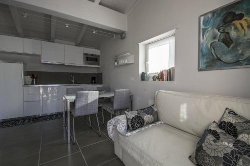 a living room with a white couch and a kitchen at Residence Il Poggio in Dorio