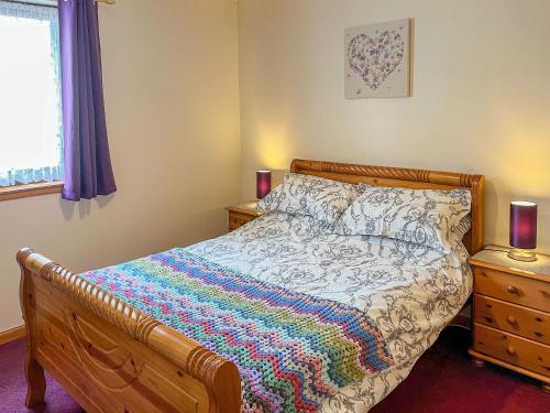 a bedroom with a bed with a colorful blanket on it at Acorn Cottage in Cononbridge