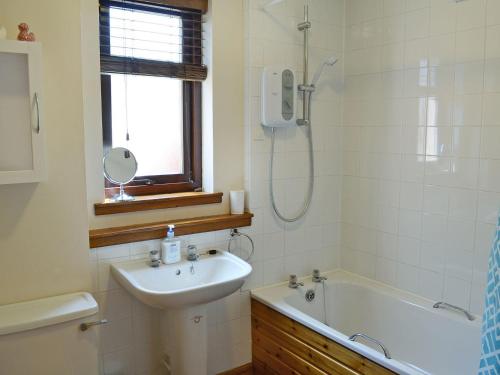 a bathroom with a sink and a tub and a shower at Acorn Cottage in Cononbridge