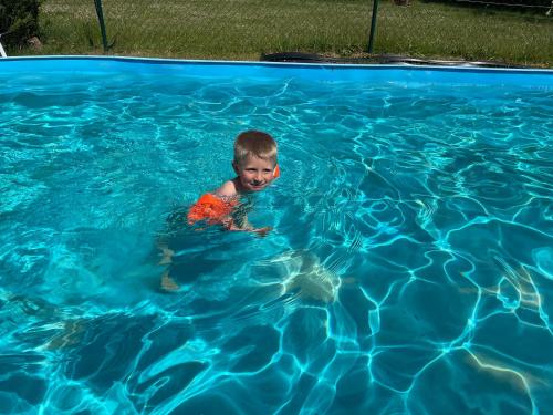 a young boy swimming in a swimming pool at Landhaus mit Pool, Bungalow in der Natur in Hohenbollentin