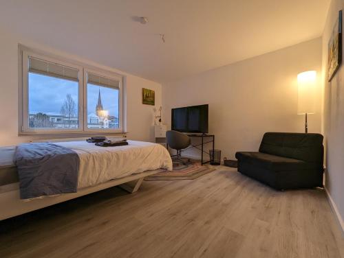 um quarto com uma cama, uma cadeira e uma televisão em Gemütliche Zimmer im Herzen der Stadt EM-APARTMENTS DEUTSCHLAND em Bielefeld
