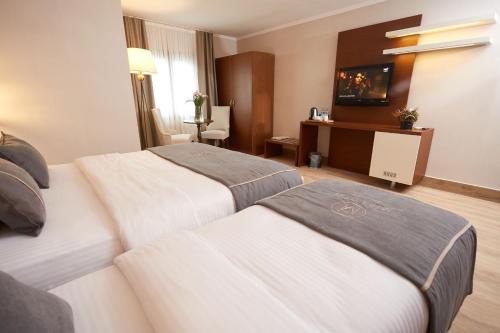 a hotel room with two beds and a desk at Mira Otel Alsancak in İzmir