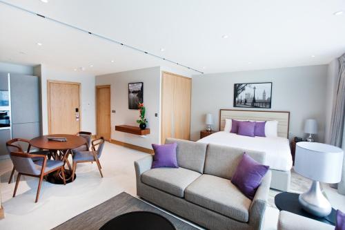 a hotel room with a bed and a couch and a table at Sanctum Belsize Road in London