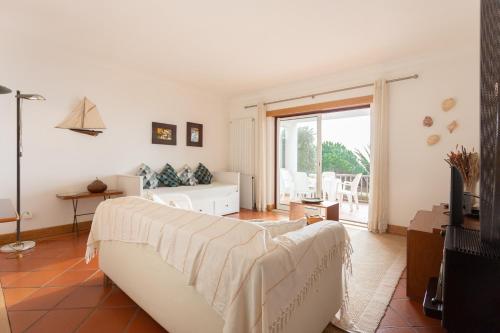 ein Wohnzimmer mit einem Sofa und einem TV in der Unterkunft Surf- Com vista para o Oceano in São Martinho do Porto