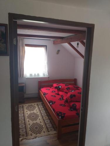 - une chambre avec un lit doté de draps rouges et une fenêtre dans l'établissement Cabana Bradul, à Colibiţa