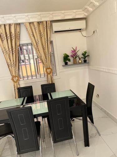 a dining room with a green table and black chairs at Appartement New Stading YAOUNDE - MIMBOMAN MAETURE in Yaoundé