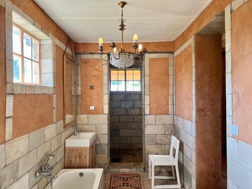 bagno con vasca, lavandino e sedia di La Locanda a Ruhengeri