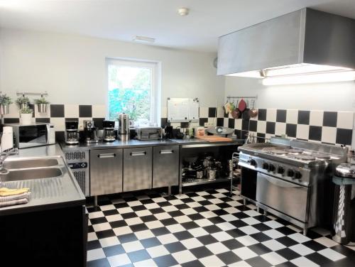 eine Küche mit Küchengeräten aus Edelstahl und einem karierten Boden in der Unterkunft La Grange de David - Access-i in Hamoir