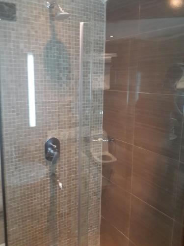 a man standing behind a glass shower door with a phone at Boma Inn Eldoret in Eldoret