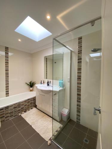 y baño con ducha acristalada y lavamanos. en Gosfords Best Location with Views, en Gosford
