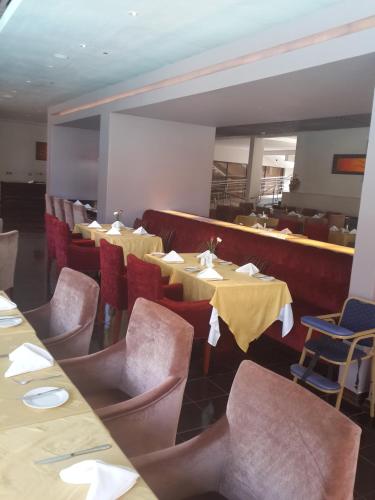 a dining room with tables and chairs with yellow tables and chairs at Boma Inn Eldoret in Eldoret