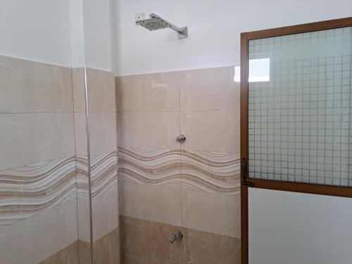 a bathroom with a shower with a glass door at B & B CHARM in Dickwella