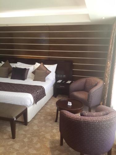 a hotel room with two beds and a chair at Boma Inn Eldoret in Eldoret