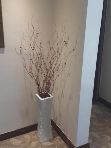 a vase with a tree with red berries in it at Boma Inn Eldoret in Eldoret
