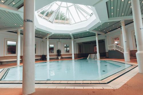 a swimming pool in a building with a skylight at Hotel MeerZeiten inklusive externer Schwimmbad- & Saunanutzung in Bensersiel