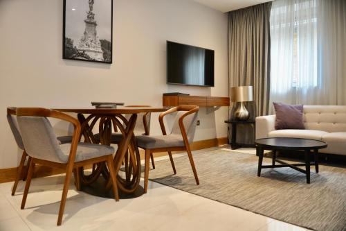 a living room with a table and chairs and a room with a television at Sanctum Belsize Road in London