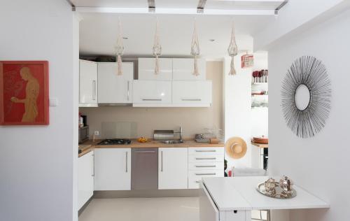 a white kitchen with white cabinets and a table at Flat With a Garden in Belem in Lisbon