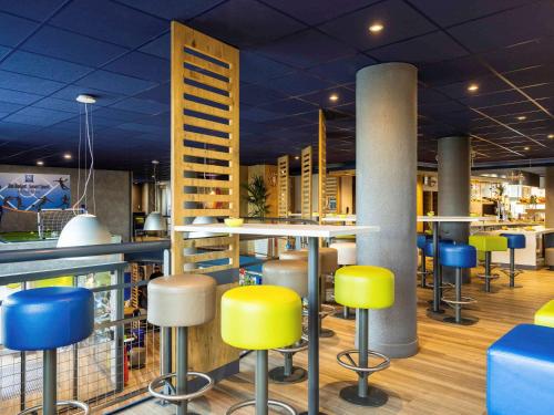 un bar con taburetes amarillos y azules en un restaurante en ibis budget Porte D'Orleans, en París