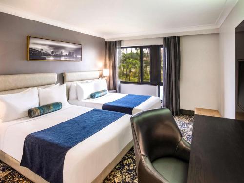 ラゴスにあるMövenpick Hotel Ikoyi Lagosのベッド2台とテレビが備わるホテルルームです。