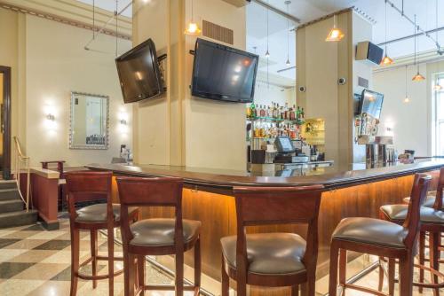 a bar with wooden chairs and a television on the wall at Ambassador Hotel Milwaukee, Trademark Collection by Wyndham in Milwaukee
