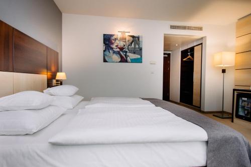 two white beds in a bedroom with a painting on the wall at Ruben Hotel Zielona Góra in Zielona Góra