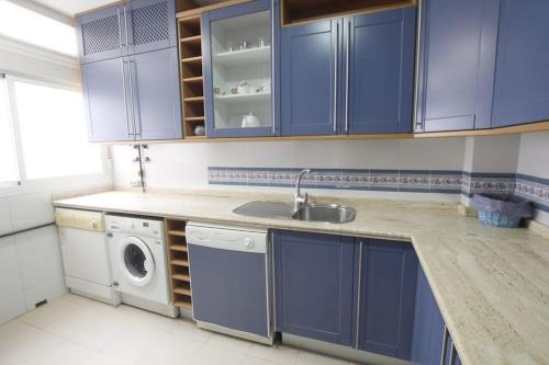 a kitchen with blue cabinets and a washing machine at Sevilla Clásica: amigos y familia. Parking gratis! in Seville