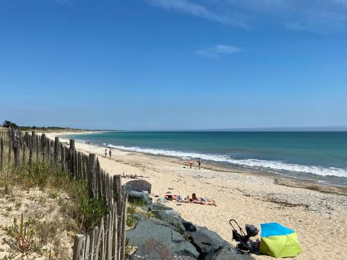 a beach with a fence and people on the beach at Appartement en duplex avec balcon, 5 minutes plage et centre village in La Couarde-sur-Mer