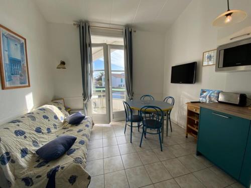 a living room with a couch and a table with chairs at Appartement en duplex avec balcon, 5 minutes plage et centre village in La Couarde-sur-Mer