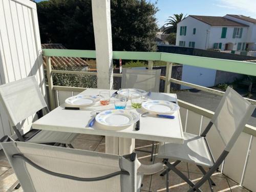 d'une table et de chaises blanches sur un balcon. dans l'établissement Appartement en duplex avec balcon, 5 minutes plage et centre village, à La Couarde-sur-Mer